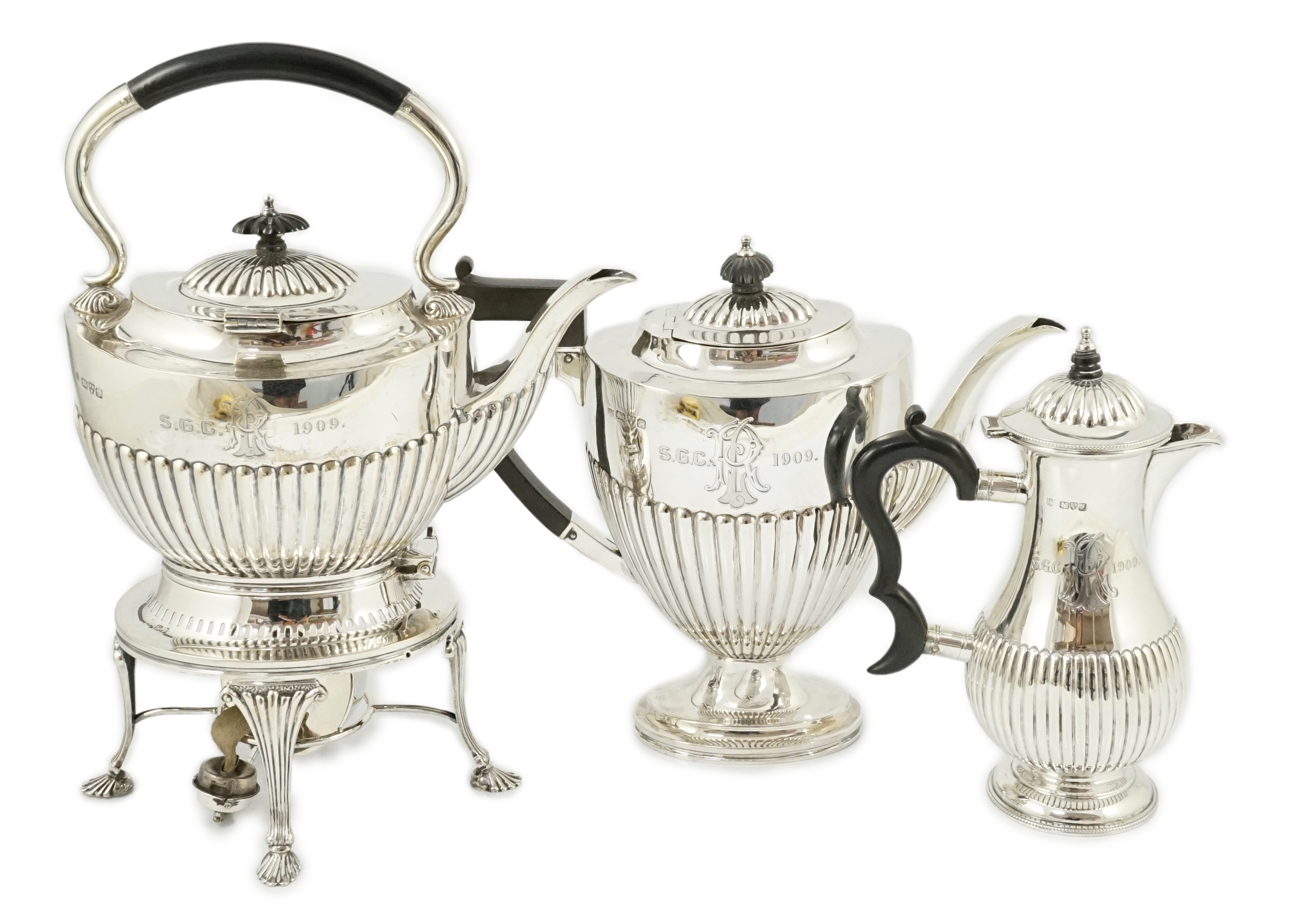 An Edwardian demi-fluted silver tea kettle on stand with burner, with matching pedestal coffee pot and hot water pot, by Barker Brothers